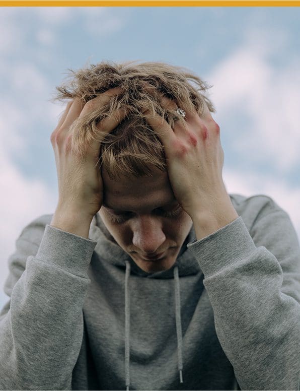 A man expressing frustration with hands on his head.