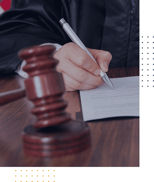 A judge writes notes with a gavel in the foreground.